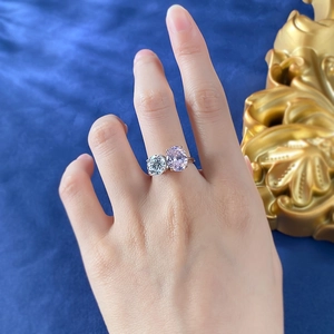 Close-up of dual-stone ring with oval pink diamond and round zircon on a model's hand