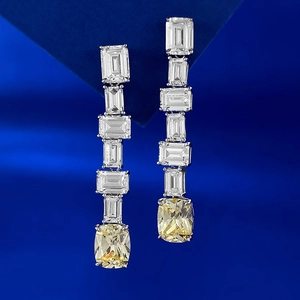 Détail de boucles d'oreilles en argent S925 avec pierres taille émeraude et diamants jaunes