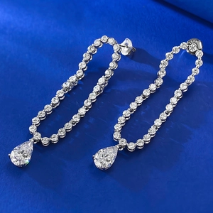 Macro detail of S925 sterling silver stamp and pear-cut drop earrings on blue silk