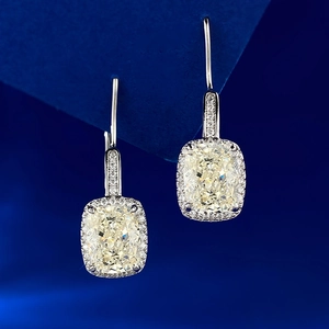 Detail shot of cushion-cut yellow lab diamond earrings on deep blue velvet background