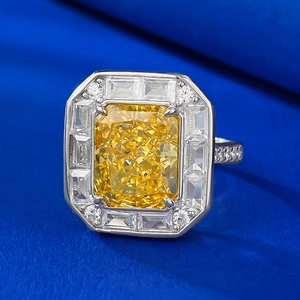Macro shot of 4-carat radiant cut yellow gem ring with diamond halo on blue silk
