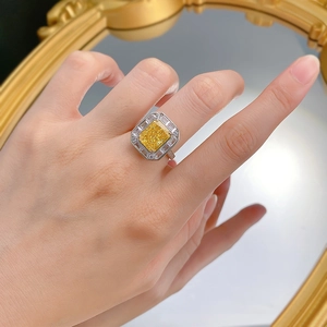 Detail of a 925 silver halo ring with a yellow radiant cut stone worn by a model