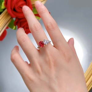 Close-up of Toi et Moi silver ring with red radiant and heart-cut stones on a hand