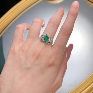 Close-up of marquise-cut emerald ring with hollow leaf pattern on female finger