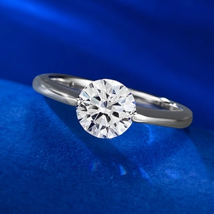 Macro detail of a sparkling 1-carat round brilliant cut diamond ring on blue velvet