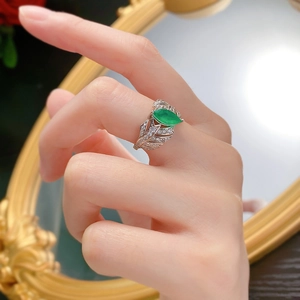 Macro detail of leaf-shaped silver ring featuring marquise emerald and pave set diamonds