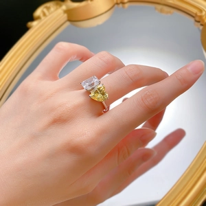 Dettaglio dell'anello a doppia pietra con cuore giallo e diamante taglio smeraldo sulla mano