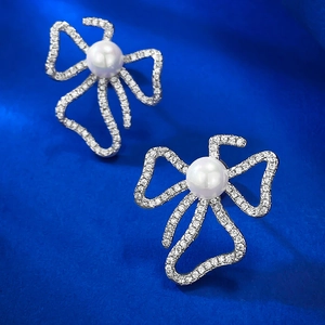S925 silver bow stud earrings with 6mm pearls and micro-pave zircons on blue background