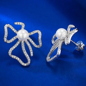 Detail of 925 sterling silver bow earrings with micro-paved zircon and 6mm white pearls