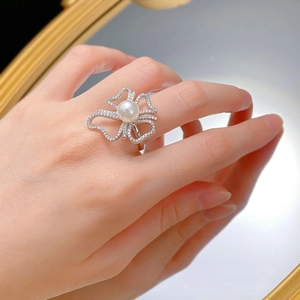 Gros plan d'une bague nœud en argent 925 avec perle naturelle 8mm et zircons au doigt