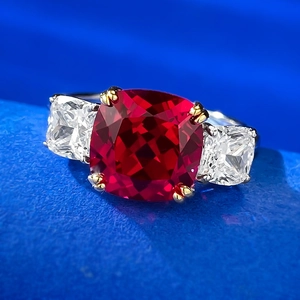 Macro shot of cushion-cut pigeon blood ruby ring with two-tone three-stone setting