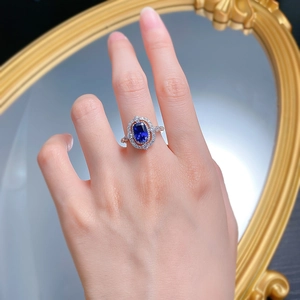 Detail of an S925 silver ring featuring an oval blue sapphire with double halo diamonds