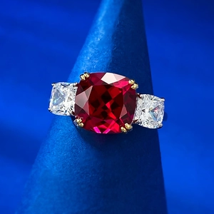 Macro shot of 925 silver three-stone ring with red cushion-cut gem and side stones