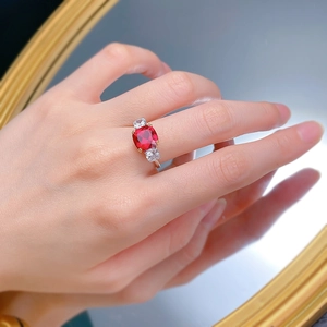 Detailed close-up of a cushion-cut ruby red ring with side square zircon accents