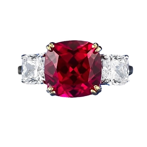 Three-stone ring featuring a cushion-cut red ruby centerpiece with clear side diamonds