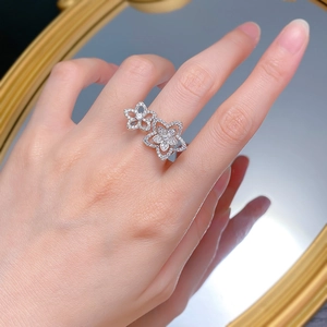 Elegant S925 silver double flower ring with pavé crystals on a model's hand by a mirror