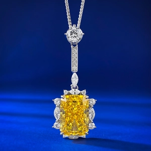Radiant cut yellow gemstone pendant necklace with marquise white stones on blue velvet