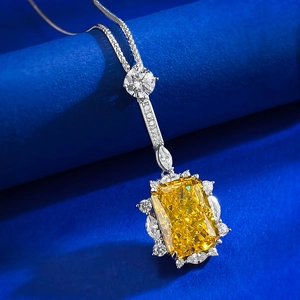 Radiant cut yellow gemstone pendant necklace with marquise diamond halo on blue backdrop