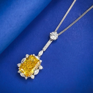 Macro detail of radiant cut yellow gemstone pendant with diamond halo on navy blue background