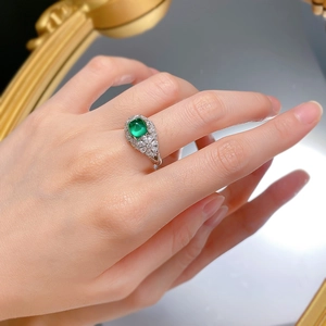 Close-up of S925 silver flower ring with emerald center stone worn on a finger