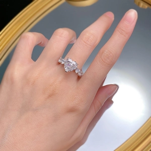 Macro d'une bague en argent avec cœur de 5 carats portée au doigt, éclairage doux