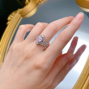 Macro shot of silver crown ring featuring square pink gemstone and layered diamond accents