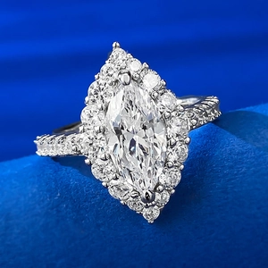 Macro shot of marquise-cut marquise white stone ring with double pavé halo on blue velvet