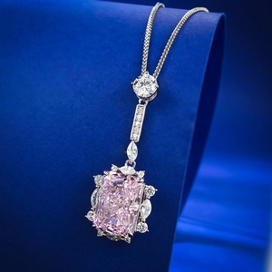Macro detail of a Radiant-cut pink gem necklace with cluster diamonds on blue velvet