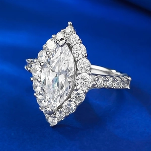 Macro side view of marquise cut diamond ring with halo stones on blue satin background