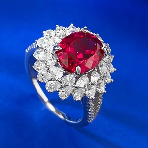 Macro shot of oval pigeon blood red stone ring with sparkling flower cluster halo setting