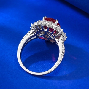 Macro shot of oval red ruby engagement ring with floral halo and pavé silver band