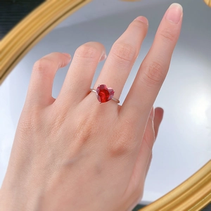 Hand mit 4 Karat herzförmigem rotem Edelsteinring mit minimalistischem s925 Silberband