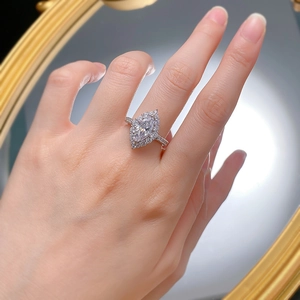 Macro detail of marquise cut halo diamond ring in platinum finish worn on finger