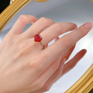 Makro-Detail eines 4-Karat-Herzrings mit rotem Edelstein und S925-Silberband am Finger