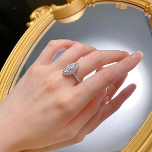 Macro shot of silver marquise cut halo ring with pavé band reflected in a mirror
