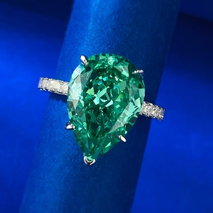 Vue macro d'une bague goutte vert émeraude 10x14mm avec anneau serti de diamants pavés