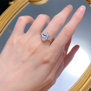 Dettaglio anello con diamante ovale e pietre laterali indossato con riflesso allo specchio