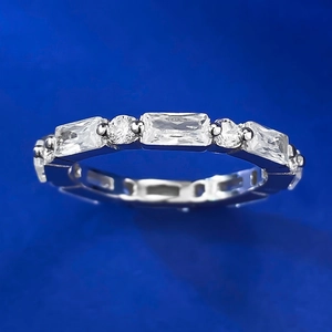 Silver baguette and round cut zircon eternity ring on a dark blue background