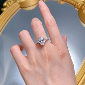 Dettaglio anello di fidanzamento ovale al dito con elegante incastonatura a tre pietre
