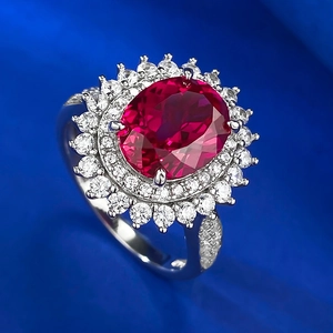 Macro detail of oval ruby cluster ring with halo diamond setting on blue velvet