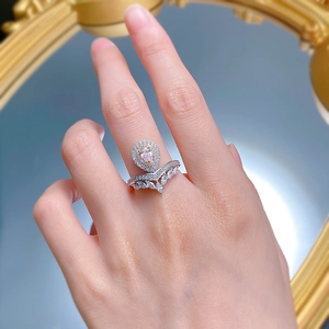 Nahaufnahme eines V-förmigen Rings mit rosa Tropfendiamant und Pavé-Besatz an der Hand