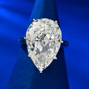 Macro view of pear-cut sparkling gemstone ring featuring multi-prong silver setting