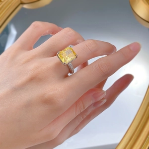 Close-up of a silver ring with a radiant cut yellow carbon diamond on a hand