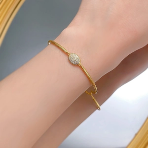 Detail of bohemian brushed gold bracelet with a pave zircon oval clasp on wrist