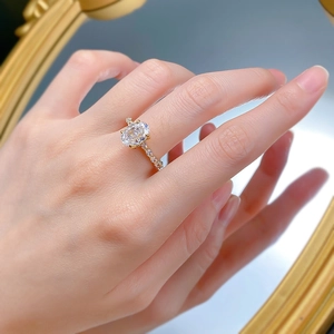 Dettaglio anello con pietra ovale e micro-pave di diamanti su fascia dorata