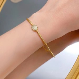 Macro view of brushed 18K gold bracelet featuring a micro-pave diamond oval charm