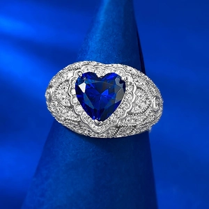 Macro shot of silver ring featuring heart-cut blue sapphire with lace pavé diamond frame