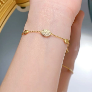Détail d'un bracelet bohème doré avec métal brossé et breloques ovales en pavé de diamants