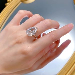 Close-up of a large pear-cut sparkling diamond ring on a model hand with reflection
