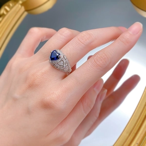 Detailed view of heart-cut blue sapphire ring with micro-pave diamond accents on finger